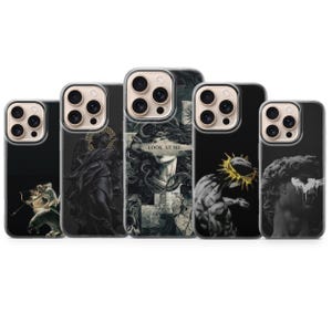 May include: Five smartphone cases featuring dark, classical art-inspired designs. The center case displays a Medusa figure with the text "LOOK AT ME" across the eyes. Other cases show a figure with a bow, a winged statue, a crowned figure, and a bust.