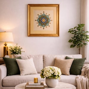 May include: Living room scene with a beige sofa, decorative pillows, and a round marble coffee table. A framed artwork with a gold border hangs above the sofa. A small potted plant and a table lamp add to the decor.