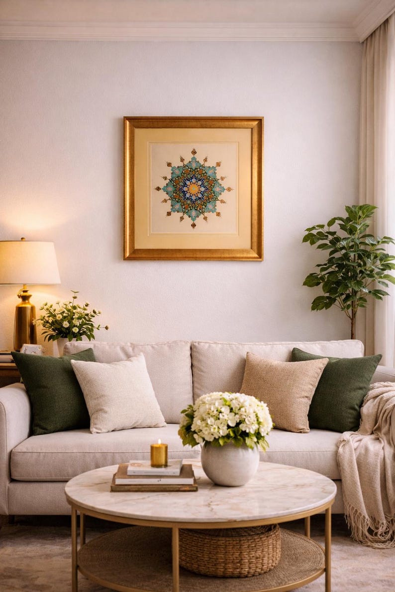 May include: Living room scene with a beige sofa, decorative pillows, and a round marble coffee table. A framed artwork with a gold border hangs above the sofa. A small potted plant and a table lamp add to the decor.
