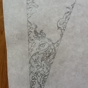 May include: A pencil sketch of a triangular design featuring intricate floral and foliate patterns. The detailed artwork is rendered in fine lines, showcasing a delicate and ornamental style, possibly for a decorative or artistic project.