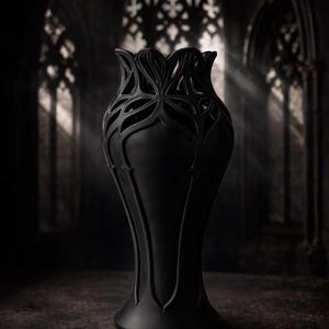 May include: A tall, black vase with a unique, openwork floral design at the top. The vase has a slender, elongated shape and sits on a flared base. The background is a dark, gothic-style interior with arched windows.