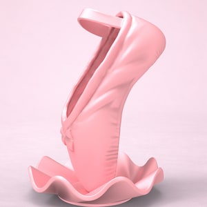 May include: A solid light pink sculpture shaped like a ballet slipper standing upright on a circular base with a wavy, ruffled edge. The slipper features a smooth, matte finish, a defined heel, and a small bow detail at the front toe area.