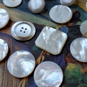May include: A collection of white mother of pearl buttons of various shapes and sizes. The buttons are arranged on a magazine page with the word "SEPTEMBER" visible.