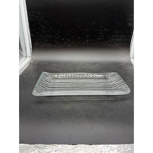 May include: A rectangular clear glass tray featuring a textured surface with parallel vertical ridges running along the length and a delicate etched leaf pattern detail centered along the top edge of the glass serving piece.
