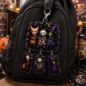 May include: A black backpack featuring a large, multi-piece hanging charm. The charm displays three characters in Halloween costumes, including a devil, a skeleton, and a witch, with three smaller individual character charms hanging below them.