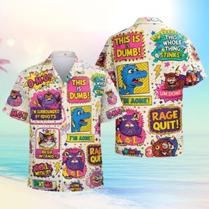 Puede incluir: Camisa de manga corta con un diseño colorido y caricaturesco. La camisa presenta varios personajes de dibujos animados y bocadillos de texto con frases como "This is Dumb!" y "Rage Quit!" sobre un fondo crema.