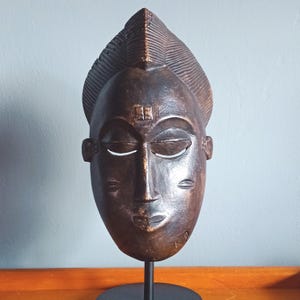 Op de afbeelding: Een witte keramische mok met een zwarte handgreep en de tekst "But First, Coffee" in een zwarte, vette letter. De mok staat op een wit oppervlak. De mok is 10 cm hoog.