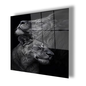 May include: A rectangular wall art piece featuring a black and white photographic print of two lions. The upper lion is positioned with its head tilted upward, while the lower lion rests its head below, both captured in a serene, close-up profile.
