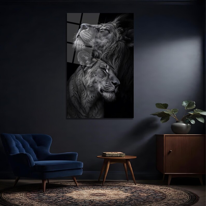 May include: A black and white wall art print featuring a close-up portrait of a lion and a lioness. The male lion is positioned behind the lioness, both looking upward with calm expressions. The artwork displays detailed fur textures and shadows.