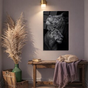 May include: A rectangular wall art print featuring a black and white portrait of two lions, one positioned above the other, with detailed fur textures and contrasting shadows, displayed in a vertical orientation on a light-colored wall.