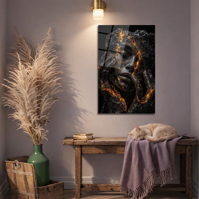 May include: A framed art print featuring a woman's face with a cracked, textured appearance. The cracks are highlighted with gold, creating a striking contrast against the dark background. The artwork is displayed on a wall.