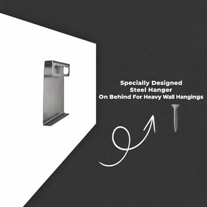 May include: A silver-colored steel hanger with a flat rectangular body and a top section featuring two oval cutouts, accompanied by a single metal screw. The text reads: Specially Designed Steel Hanger On Behind For Heavy Wall Hangings.