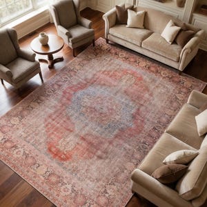 May include: A large, rectangular area rug with a distressed, vintage look. The rug features a central medallion design in shades of red, blue, and beige, surrounded by a detailed border. The rug is placed in a living room setting.