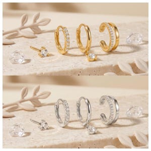 Pode incluir: Um conjunto de joias composto por um brinco de pino com uma pedra clara, uma pequena argola com uma fila de pedras claras, uma argola com uma pedra clara pendente e um ear cuff de banda dupla com uma fila de pedras claras, em ouro e prata.