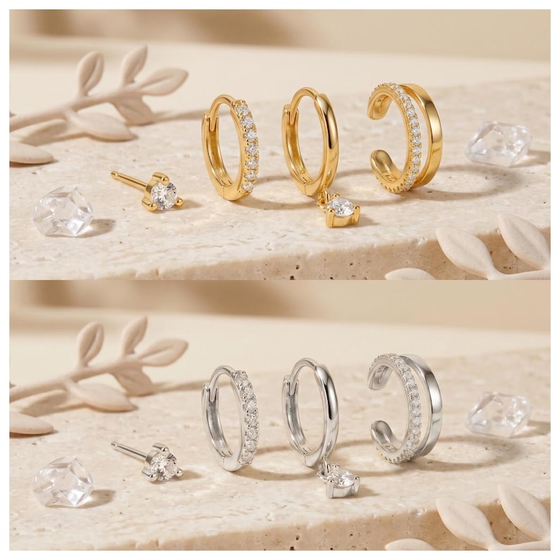 Pode incluir: Um conjunto de joias composto por um brinco de pino com uma pedra clara, uma pequena argola com uma fila de pedras claras, uma argola com uma pedra clara pendente e um ear cuff de banda dupla com uma fila de pedras claras, em ouro e prata.