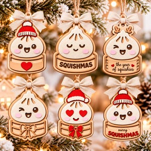 Peut inclure: Six décorations en bois en forme de raviolis dans des paniers vapeur, chacune avec un nœud en ruban beige. Les motifs incluent un bonnet rouge, un cœur, le texte SQUISHMAS, the year of squishies, un clin d'œil, des yeux en cœur et SQUISHMAS.