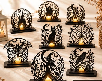 May include: A bundle of nine black laser-cut Halloween candle light frames featuring intricate silhouettes of a haunted castle, ghost, owl, cat, spider web, bat, witch, and raven, each mounted on a rectangular base with a small tea light candle.