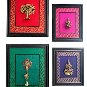 May include: Four framed wall art pieces. Each frame is black with a textured design. The art features gold-colored metal sculptures on backgrounds of red, pink, green, and purple fabric. The sculptures include a tree, a deity, and ornate shapes.