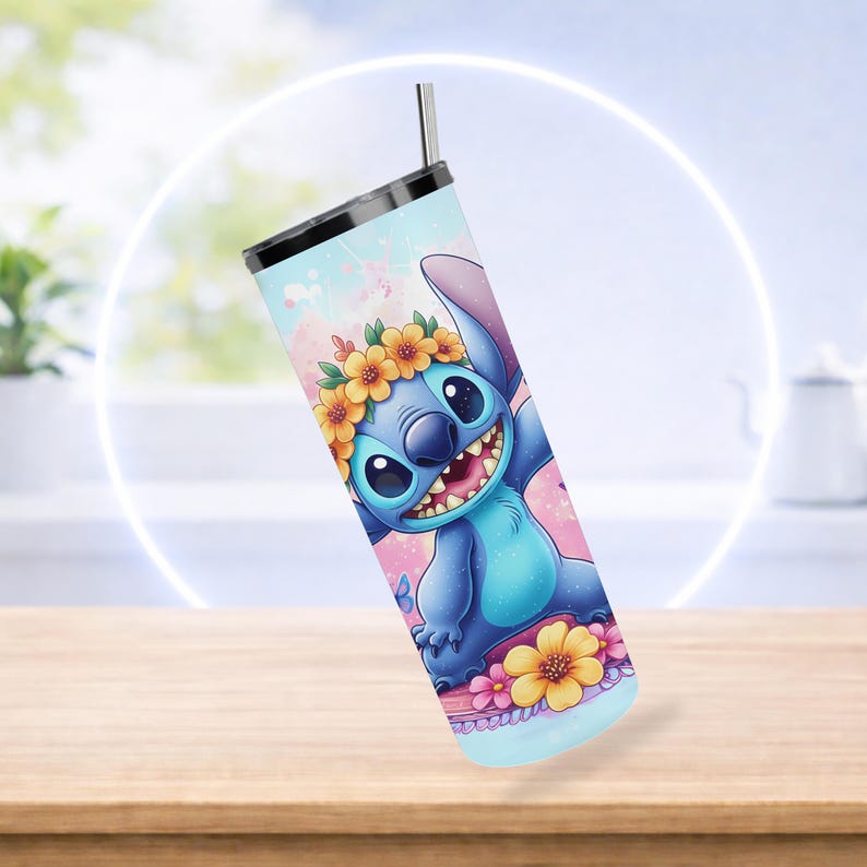 Pode incluir: Caneca azul com um personagem de desenho animado usando uma coroa de flores. A caneca tem um canudo prateado e uma tampa preta. O design apresenta um esquema de cores azul claro, rosa e amarelo. Em uma mesa de madeira.