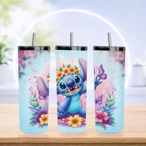 Pode incluir: Tr&ecirc;s canecas de a&ccedil;o inoxid&aacute;vel com tampas e canudos. Cada caneca apresenta uma ilustra&ccedil;&atilde;o de desenho animado de Stitch, rodeado por flores e borboletas, em um fundo azul claro com detalhes em aquarela rosa. As canecas est&atilde;o em uma superf&iacute;cie de madeira.
