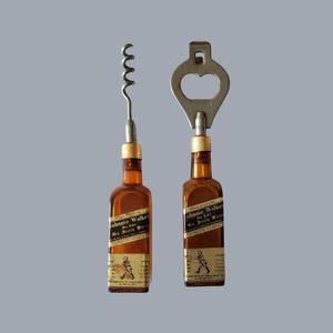 May include: Two bar tools: a corkscrew and a bottle opener. Both are designed with brown bottle-shaped handles featuring labels. The corkscrew has a silver spiral, and the bottle opener has a keyhole-shaped top. The background is a solid gray.
