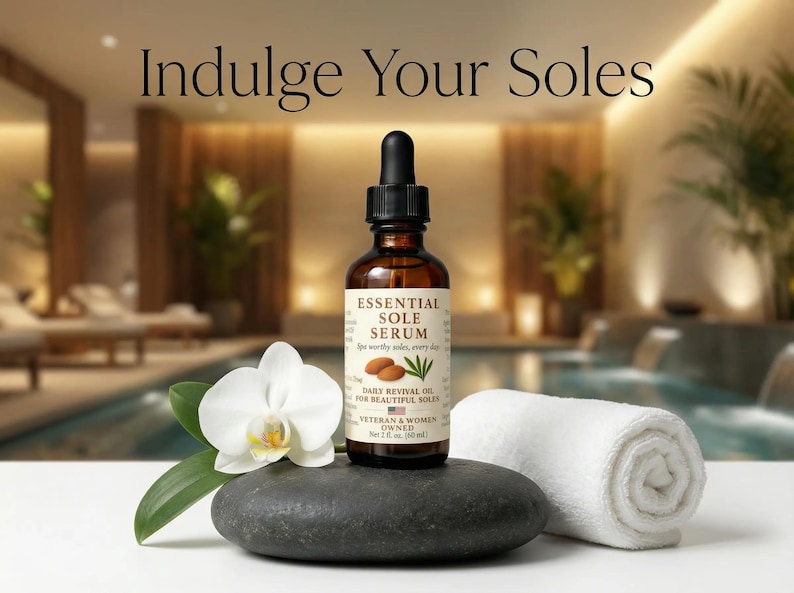 Puede incluir: Una botella de vidrio marr&oacute;n de Essential Sole Serum con un cuentagotas negro, ilustraciones de almendras y hojas, y el texto "Indulge Your Soles". Una orqu&iacute;dea blanca, una piedra negra y una toalla blanca enrollada est&aacute;n en primer plano.