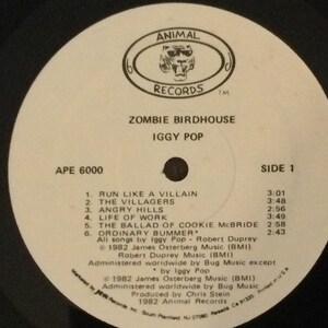 May include: A black vinyl record with a white label featuring the text "ZOMBIE BIRDHOUSE" by Iggy Pop. The label includes a logo for Animal Records and a list of songs, including "Run Like a Villain" and "Angry Hills."