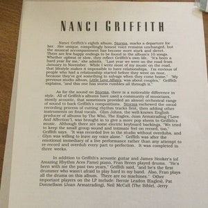 May include: A printed page featuring text about Nanci Griffith's album "Storms." The text is in a serif font and includes details about the album's musical style, recording process, and personnel. The page is on a light-colored background.