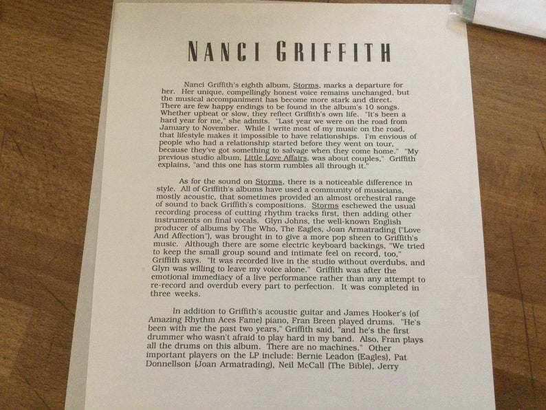 May include: A printed page featuring text about Nanci Griffith's album "Storms." The text is in a serif font and includes details about the album's musical style, recording process, and personnel. The page is on a light-colored background.