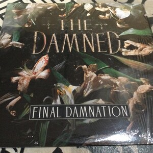 May include: A vinyl record album titled "The Damned: Final Damnation." The album cover features a dark, floral design with the band's name in gold lettering. The artwork includes dried flowers and green leaves.