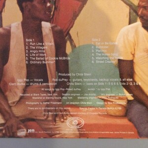 May include: Album cover featuring two men seated in front of a colorful mural. The album's tracklist is visible, including songs like "Run Like a Villain" and "Eat or Be Eaten." The album credits Iggy Pop, Clem Burke, and Chris Stein.