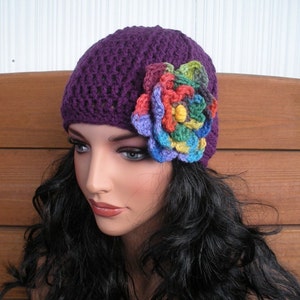 May include: Purple crocheted beanie with a colorful crocheted flower embellishment.