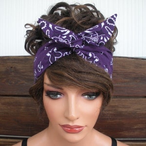 May include: Purple bandana headband with a white paisley pattern. The headband is tied in a knot at the top of the head.