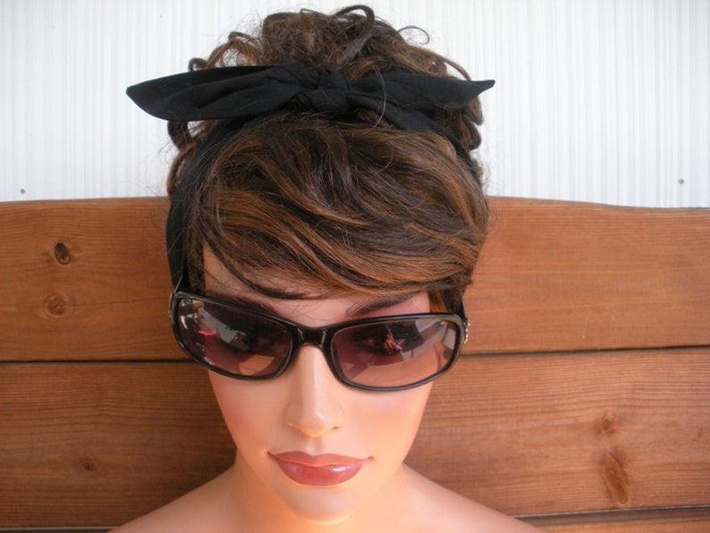 May include: A woman with brown hair wearing black sunglasses and a black headband tied in a bow.