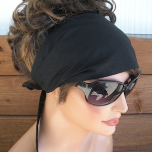 May include: A black fabric headband with a long tie, worn by a person with brown hair and sunglasses.