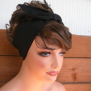May include: A black headband with a bow tied on top. The headband is made of a soft, stretchy fabric.