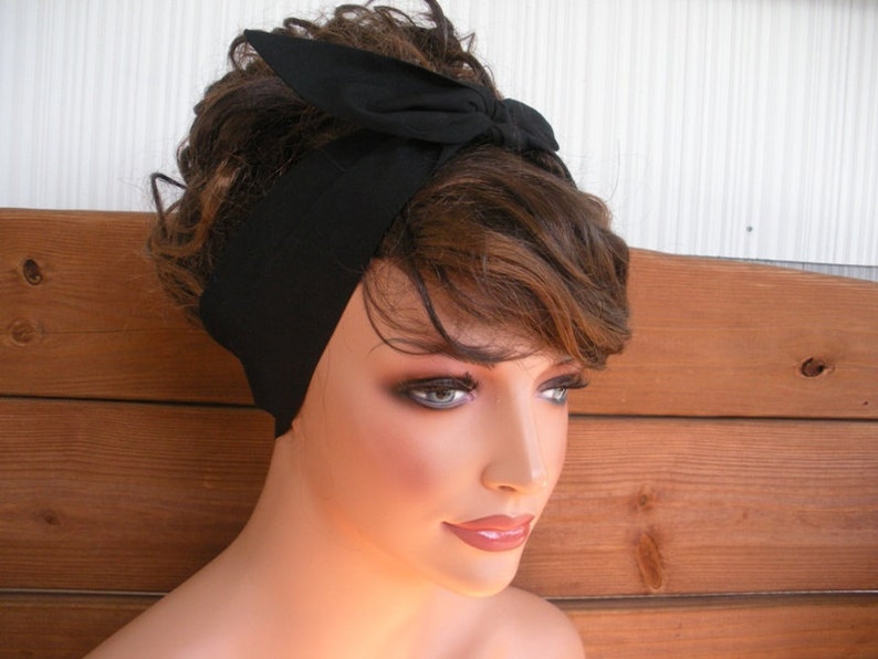 May include: A black headband with a bow tied on top. The headband is made of a soft, stretchy fabric.