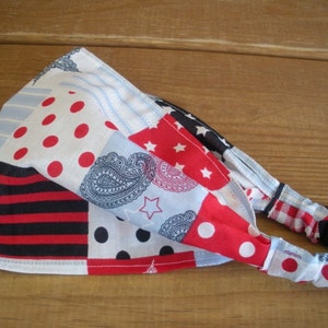 May include: A patchwork headband featuring red, white, and blue patterns. The design includes polka dots, stripes, stars, and paisley motifs. The headband is made of fabric and is designed to be worn around the head.
