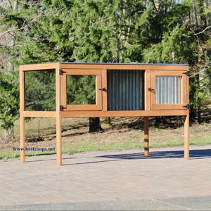 Op de afbeelding: Een houten kippenhok met een golfplaten dak en accenten. Het hok heeft een rechthoekige vorm met gaas en houten kozijnen. Het hok staat op houten poten en staat buiten tegen een achtergrond van bomen.