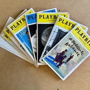 Puede incluir: Una colección de programas de teatro Playbill vintage. Cada programa presenta una pancarta amarilla con la palabra "PLAYBILL" en letras negras. Las portadas muestran varios títulos de espectáculos y obras de arte, incluyendo "A Delicate Balance" y "ARC".