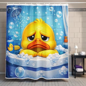Könnte beinhalten: Blauer und weißer Duschvorhang mit einer Cartoon-Ente in einer Badewanne. Die gelbe Ente hat einen traurigen Ausdruck und ist von Blasen umgeben. Ein Duschkopf und Seifenflaschen sind ebenfalls sichtbar.