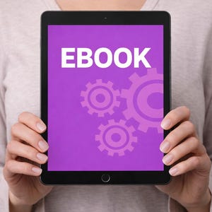 Puede incluir: Una tableta negra muestra la palabra "EBOOK" en letras blancas sobre un fondo morado. El fondo también presenta un diseño de engranajes entrelazados en un tono morado más claro. La tableta es sostenida por una persona.