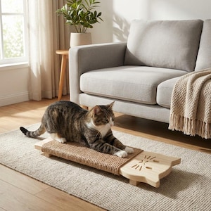 May include: A tabby cat lies on a wooden cat scratcher with a woven sisal surface. The scratcher has a light-coloured wooden base shaped like a cat's head. The cat is on a beige rug in a living room setting.
