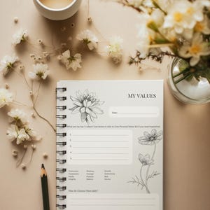 May include: A spiral-bound notebook with the words "MY VALUES" on the cover, featuring floral illustrations. The notebook is open, revealing lined pages for writing. A pencil and a cup of tea are also present, along with floral arrangements.