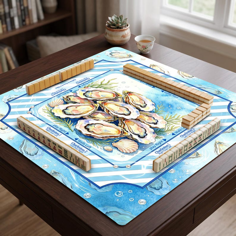 May include: A square mahjong mat featuring a watercolor illustration of oysters and seashells on a blue and white striped background. The mat includes printed game instructions and text, with four sets of mahjong tiles arranged along the edges.