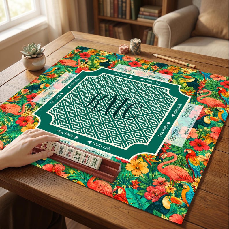 May include: A square mahjong mat featuring a vibrant tropical pattern with pink flamingos, colorful parrots, toucans, and hibiscus flowers. The center has a dark green square with a white Greek key border and the handwritten text HMC.