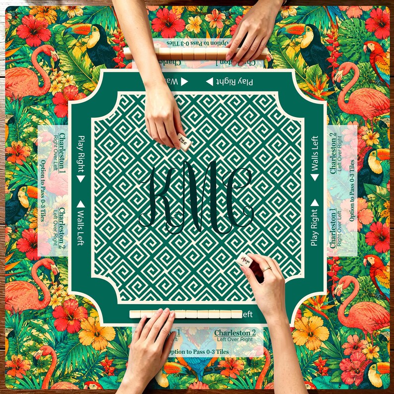 May include: A square game mat featuring a tropical pattern of pink flamingos, toucans, parrots, and red hibiscus flowers. The center has a dark green border with a white geometric pattern and the monogram KMC. Text includes Play Right, Walls Left, and Charleston.