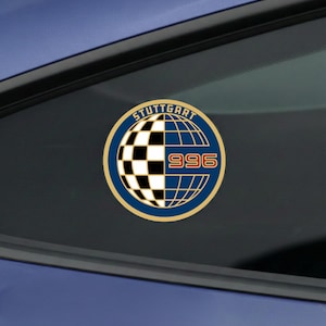 May include: A round sticker with the text "STUTTGART" arched above a checkered black and white pattern and a globe design. Below the globe is the number "996" in a gold font. The sticker has a blue and gold border.