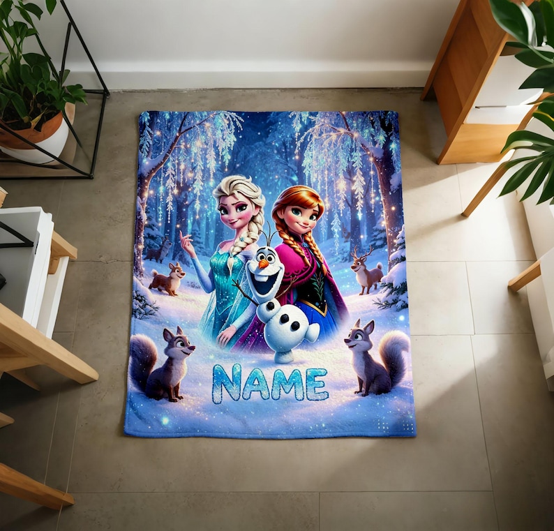 Puede incluir: Una manta rectangular de forro polar con una vibrante escena de bosque nevado con Elsa, Anna y Olaf. El dise&ntilde;o incluye peque&ntilde;os animales del bosque y la palabra NAME en letras grandes de color azul claro en la parte inferior del estampado.