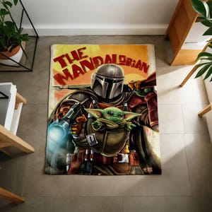 Może przedstawiać: Prostokątny dywan z grafiką The Mandalorian i Grogu z serii Gwiezdne Wojny. Dywan ma ż&oacute;łto-pomarańczowe tło z czerwonym napisem "The Mandalorian". Mandalorian jest przedstawiony w zbroi, trzymając broń i Grogu.